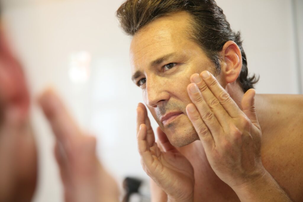 Male checking her face on a mirror for wrinkles